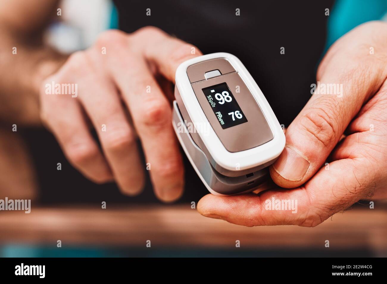 A man monitors oxygen saturation with a pulse oximeter - covid prevention Stock Photo