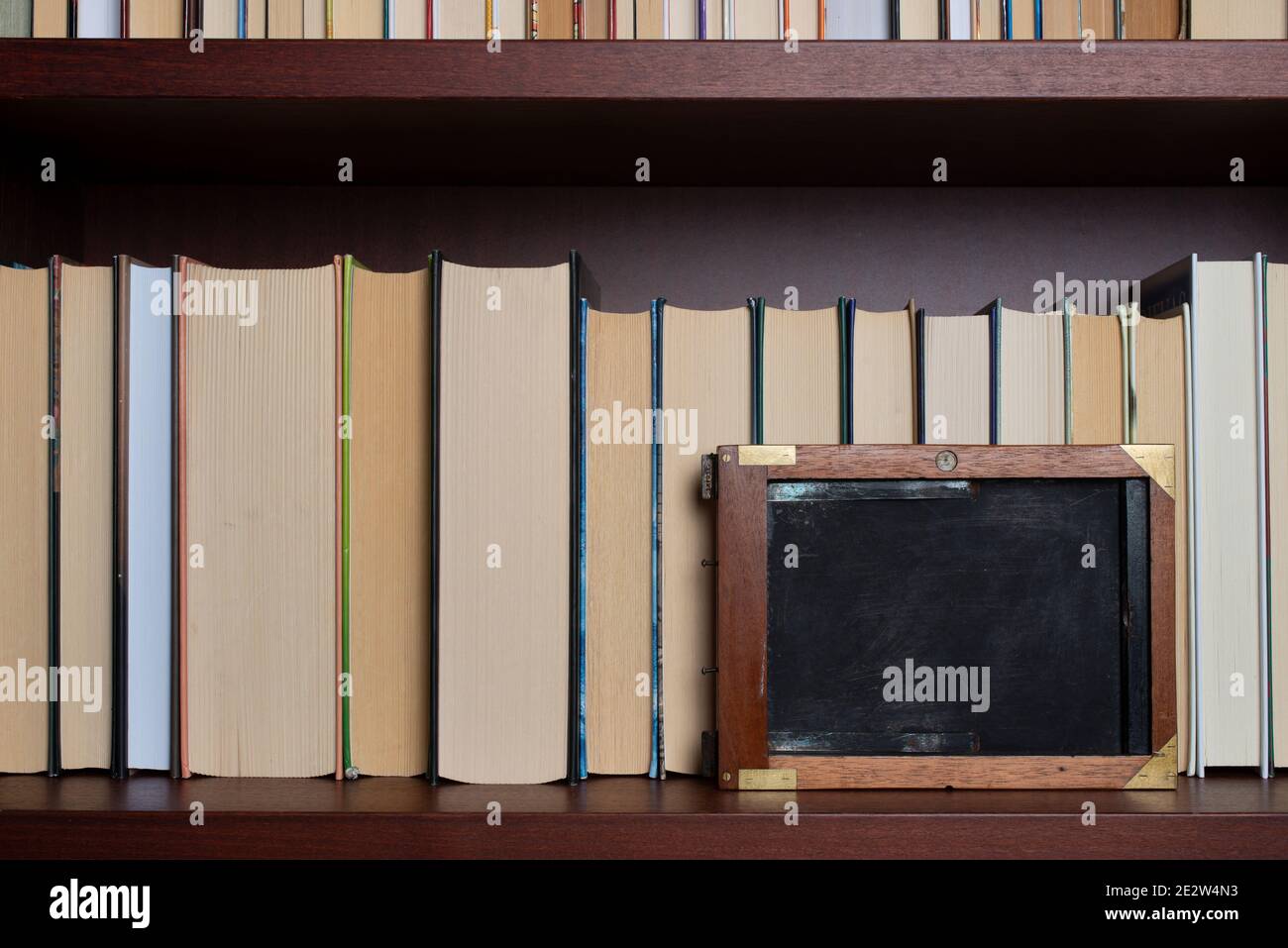 Bookshelf with books displayed backwards and vintage film plate holder