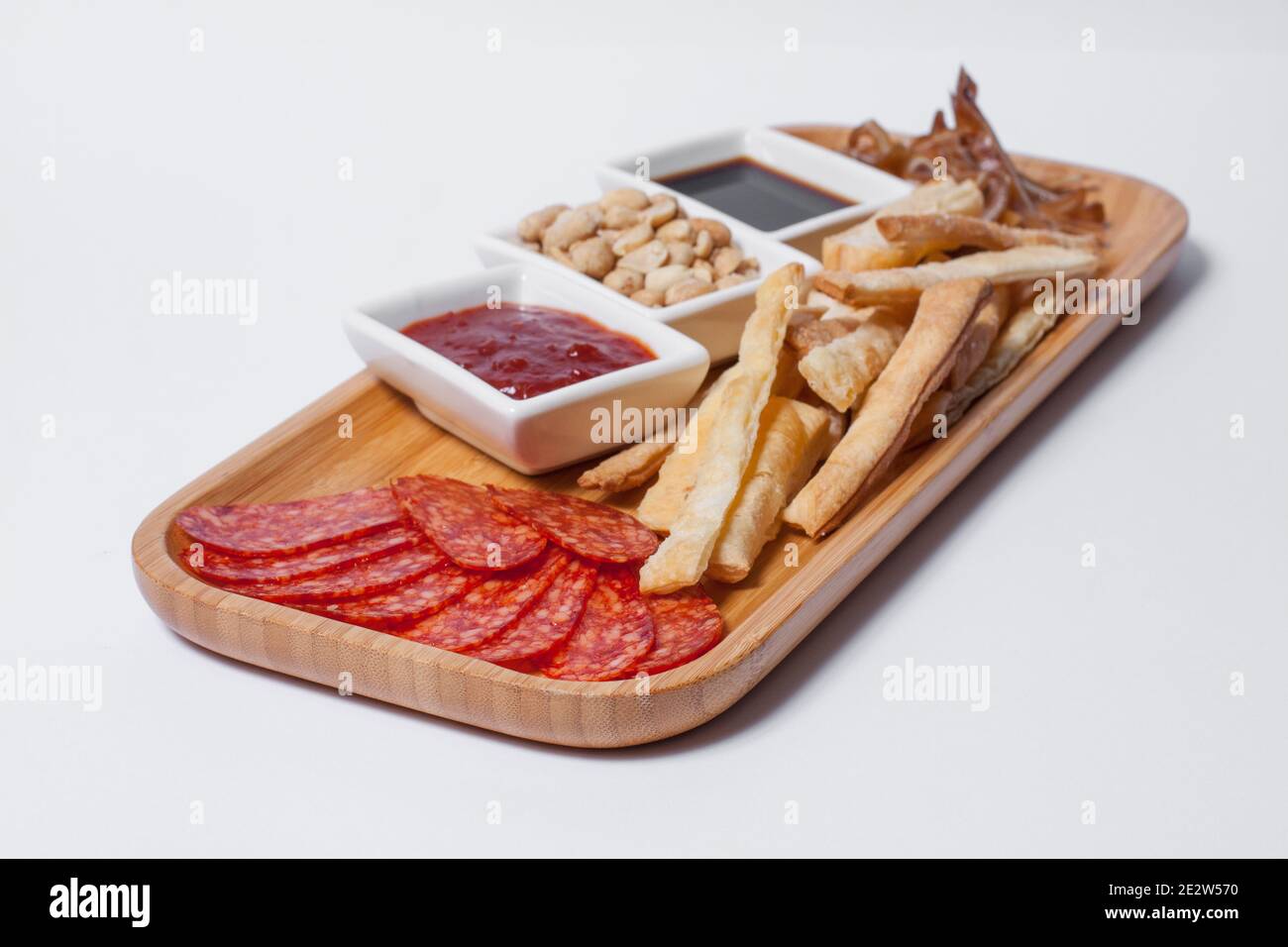 beer appetizers set with peanuts, salami, toasts, and cheese on wooden