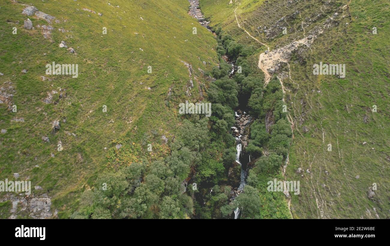 Green mountains path aerial. Rock mount stream river banks. Narrow way from hill to cloudy peak. Cinematic nobody nature landscape of Arran Island, Scotland. Summer vacation at greenery ranges Stock Photo