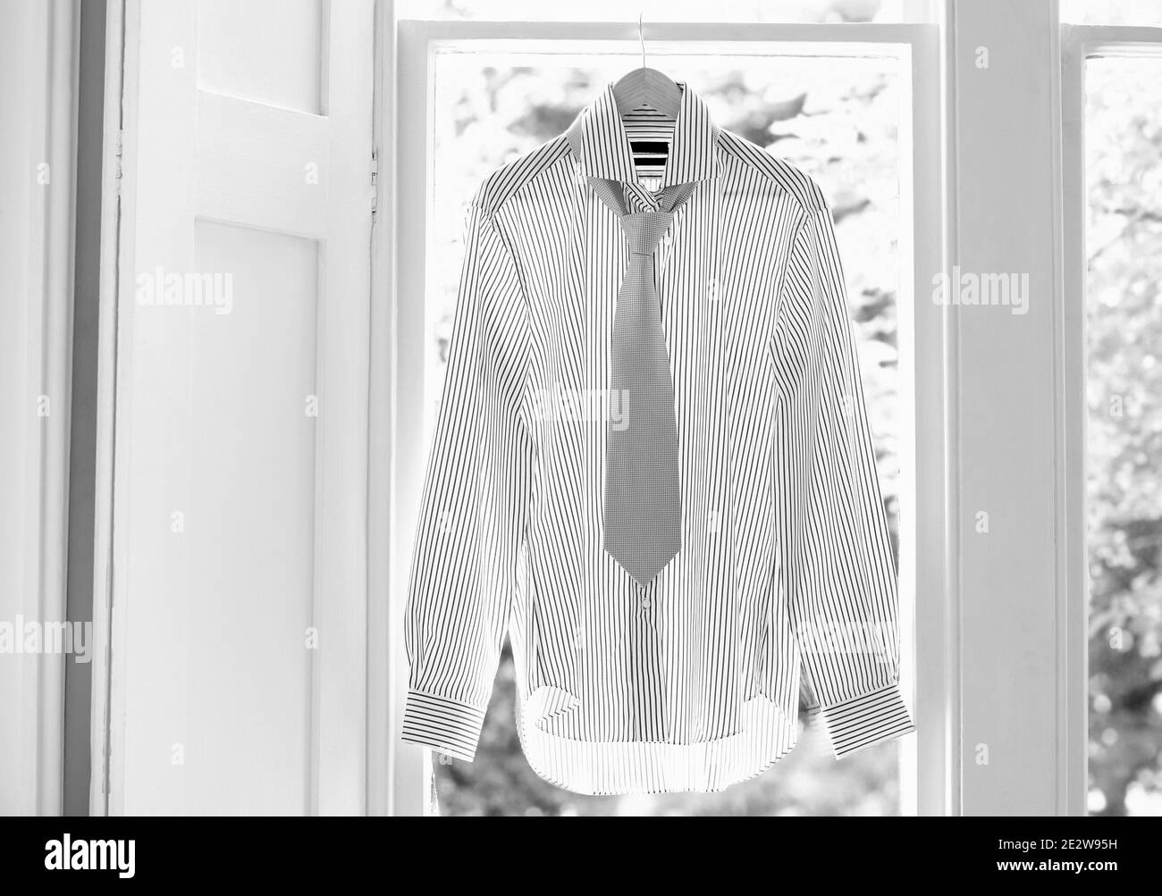 Dress shirt and tie on hanger at domestic window Stock Photo