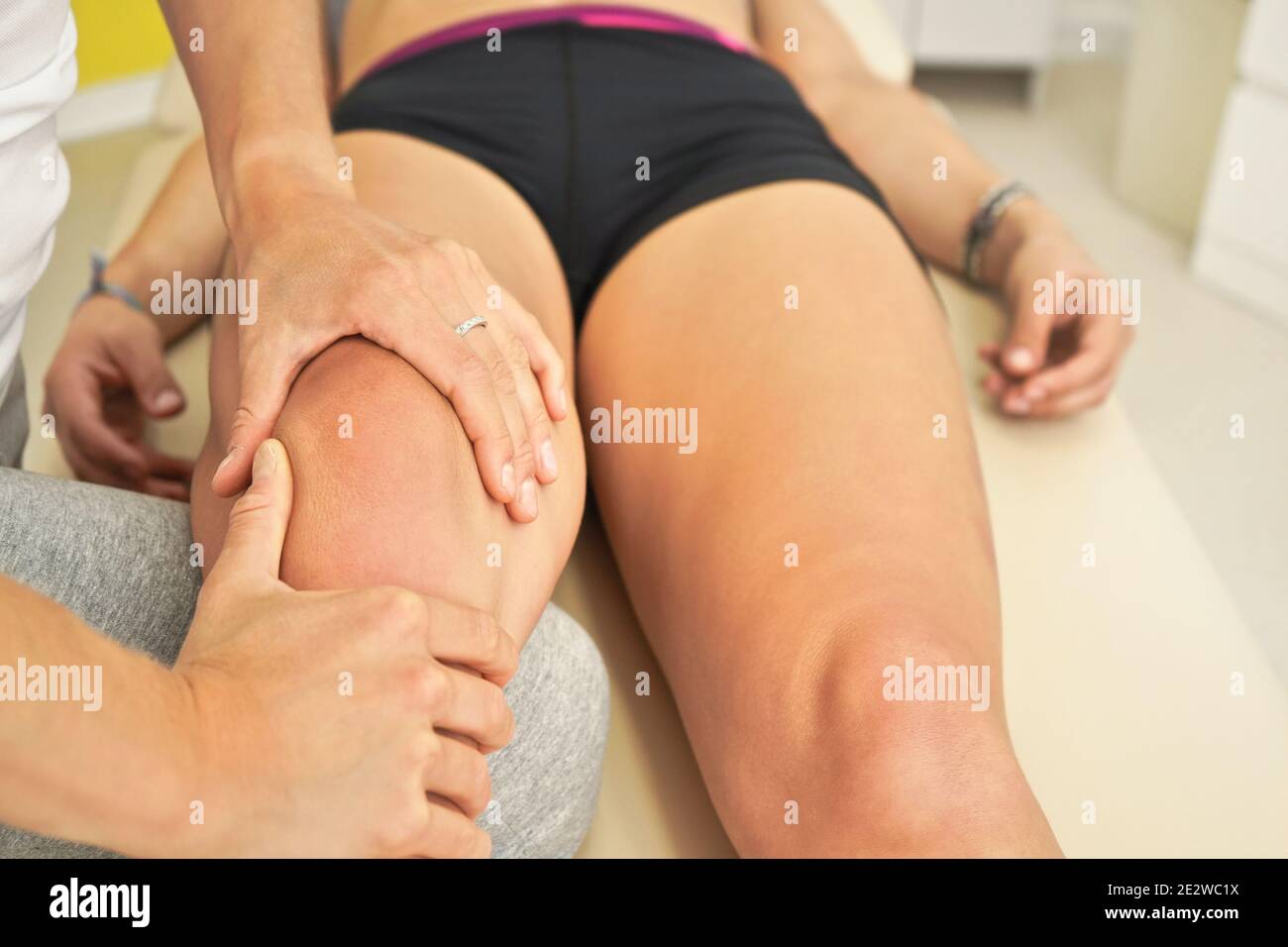 Physiotherapist massaging leg of her patient lying down on massage table Stock Photo