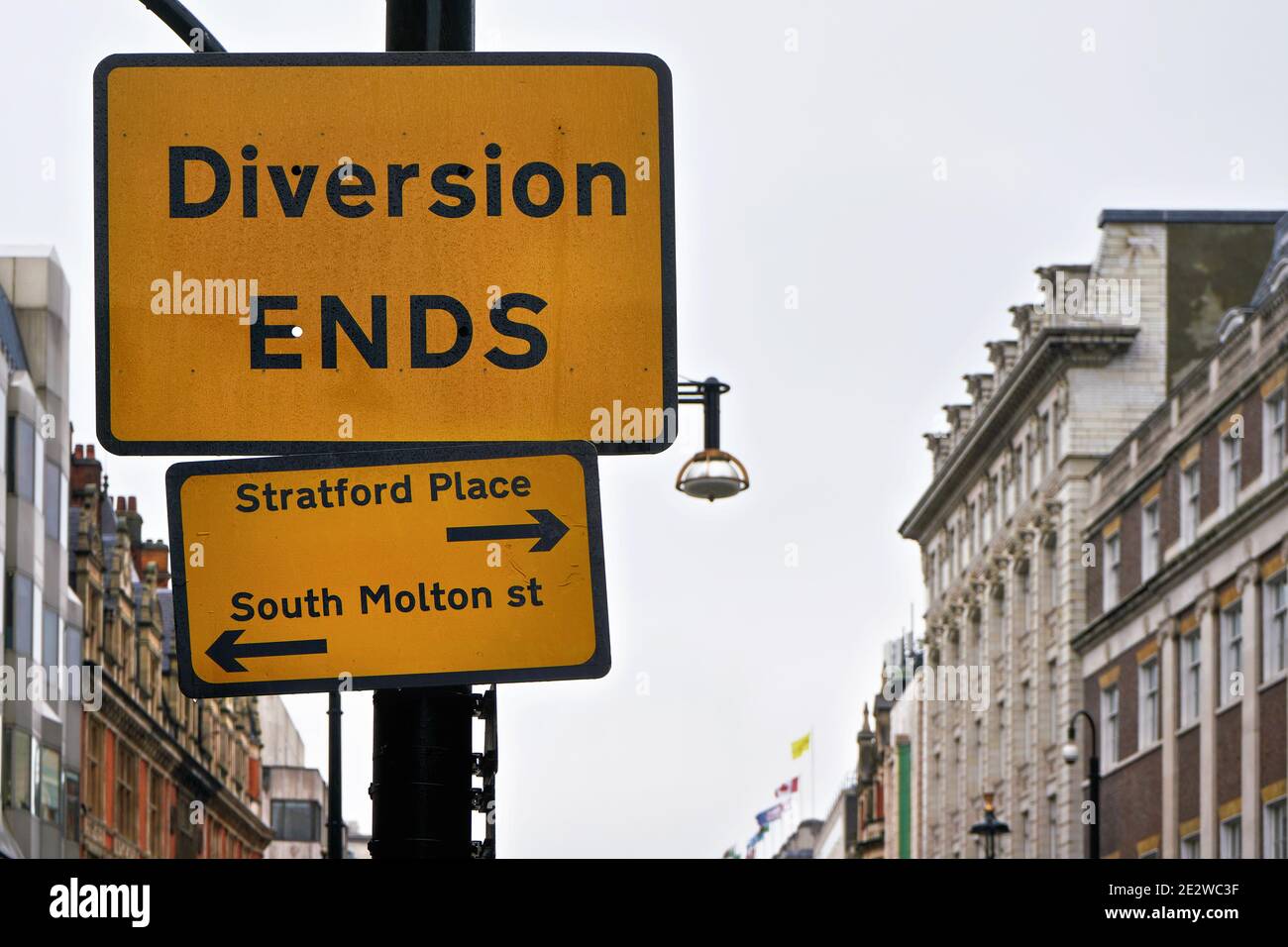 Yellow and black Diversion Ends sign with arrows pointing to Stratford Place and South Molton street, blurred building in background Stock Photo