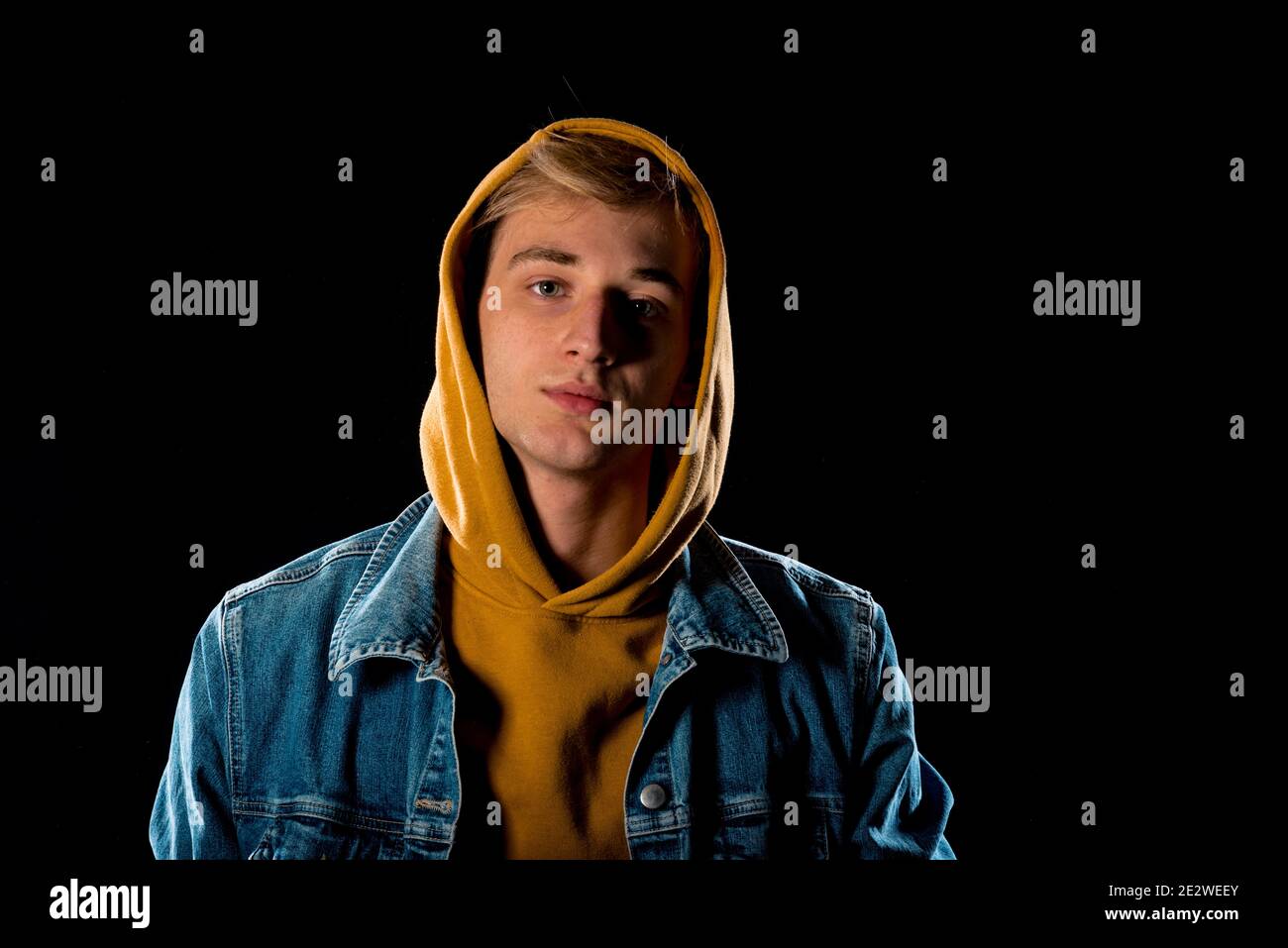 Cool young man dressed in jeans jacket and yellow hoodie Stock Photo