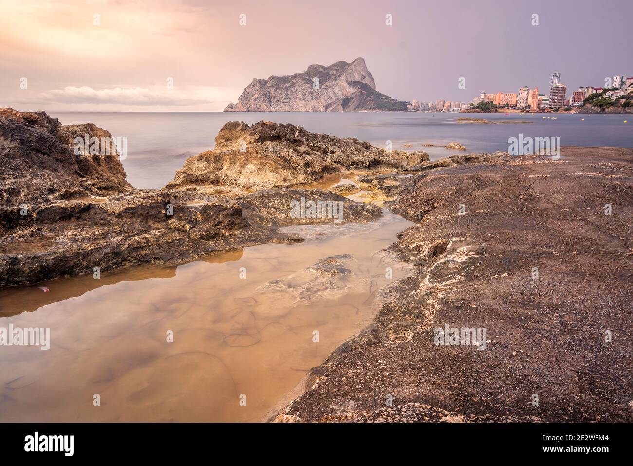 Vista del peÃ±Ã³n de Ifach desde la playa con unas rocas en primer plano Stock Photo