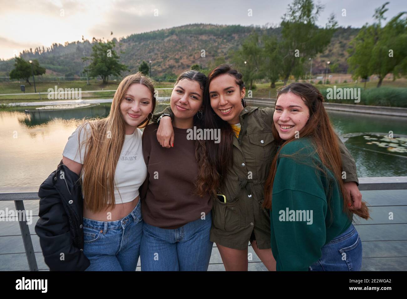 A group of beautiful young women posing near a lake in a park on a sum ...