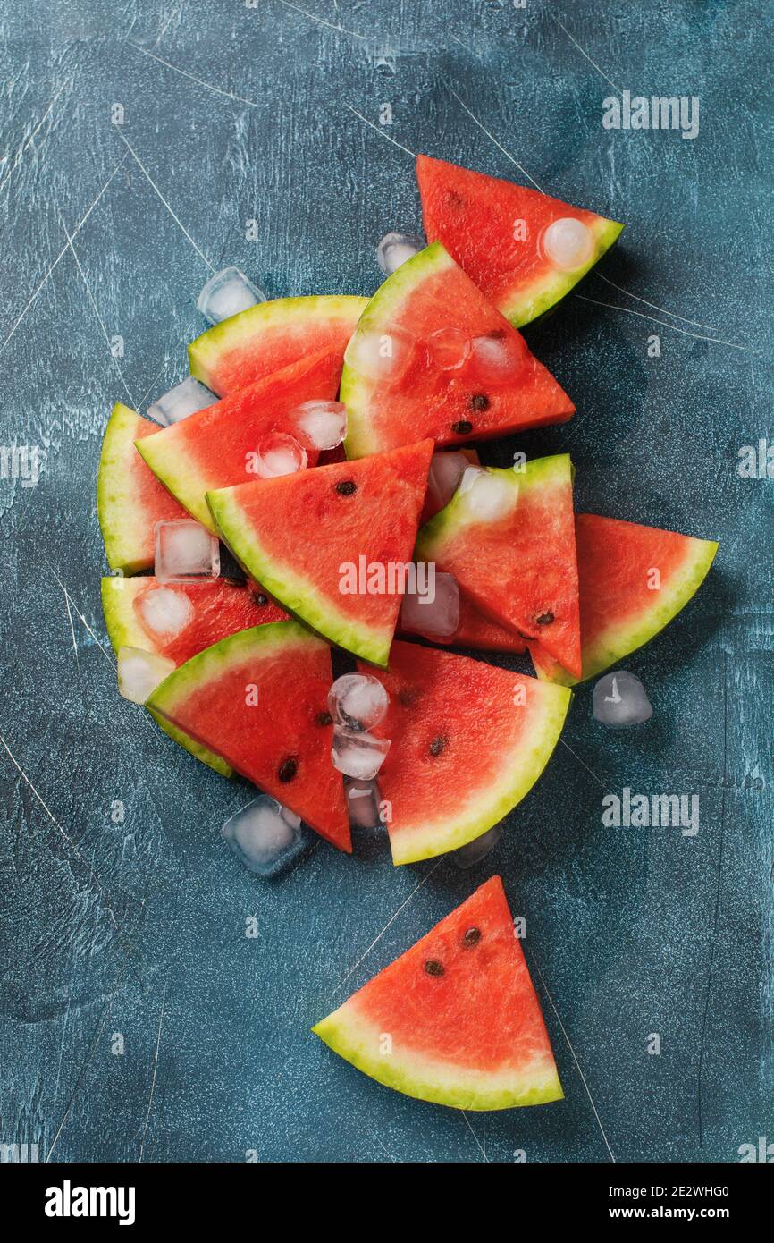 Slices of fresh watermelon with ice on a blue concrete background ...