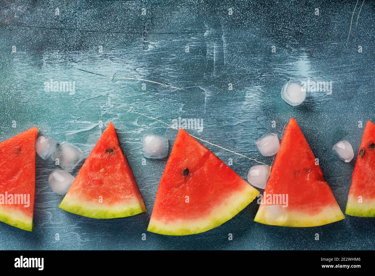 Slices of fresh watermelon with ice on a blue concrete background ...