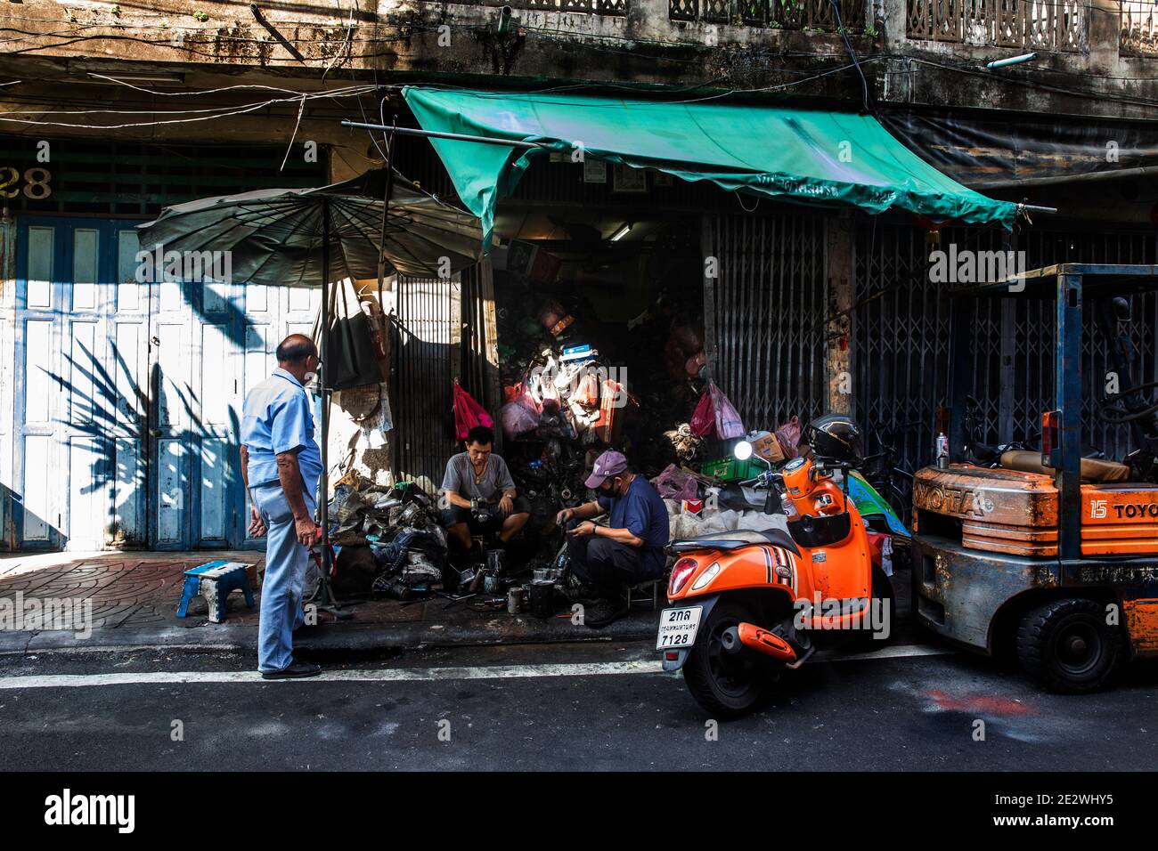 Man Watches Mechanics work on Auto Parts in Talat Noi of Bangkok Stock