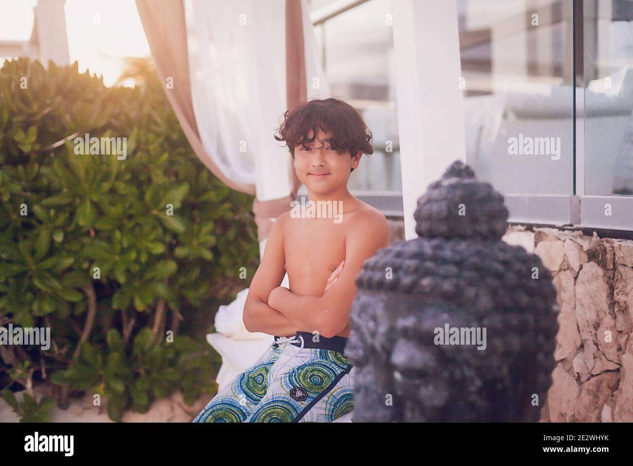 Smiling pre teen boy with arms crossed on a tropical beach. Stock Photo