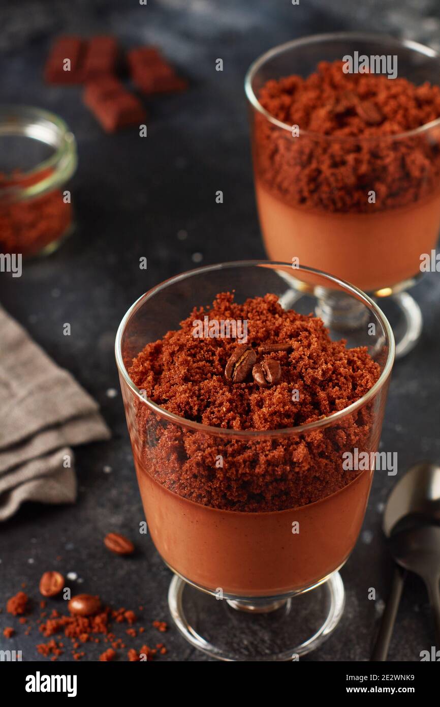 Delicious dessert chocolate mousse with brownie in glass jars on a light slate, stone or
