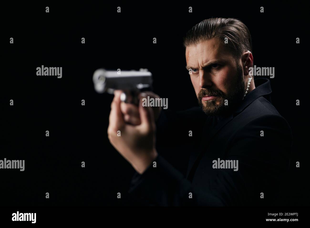 Serious man aiming with gun over black background Stock Photo - Alamy