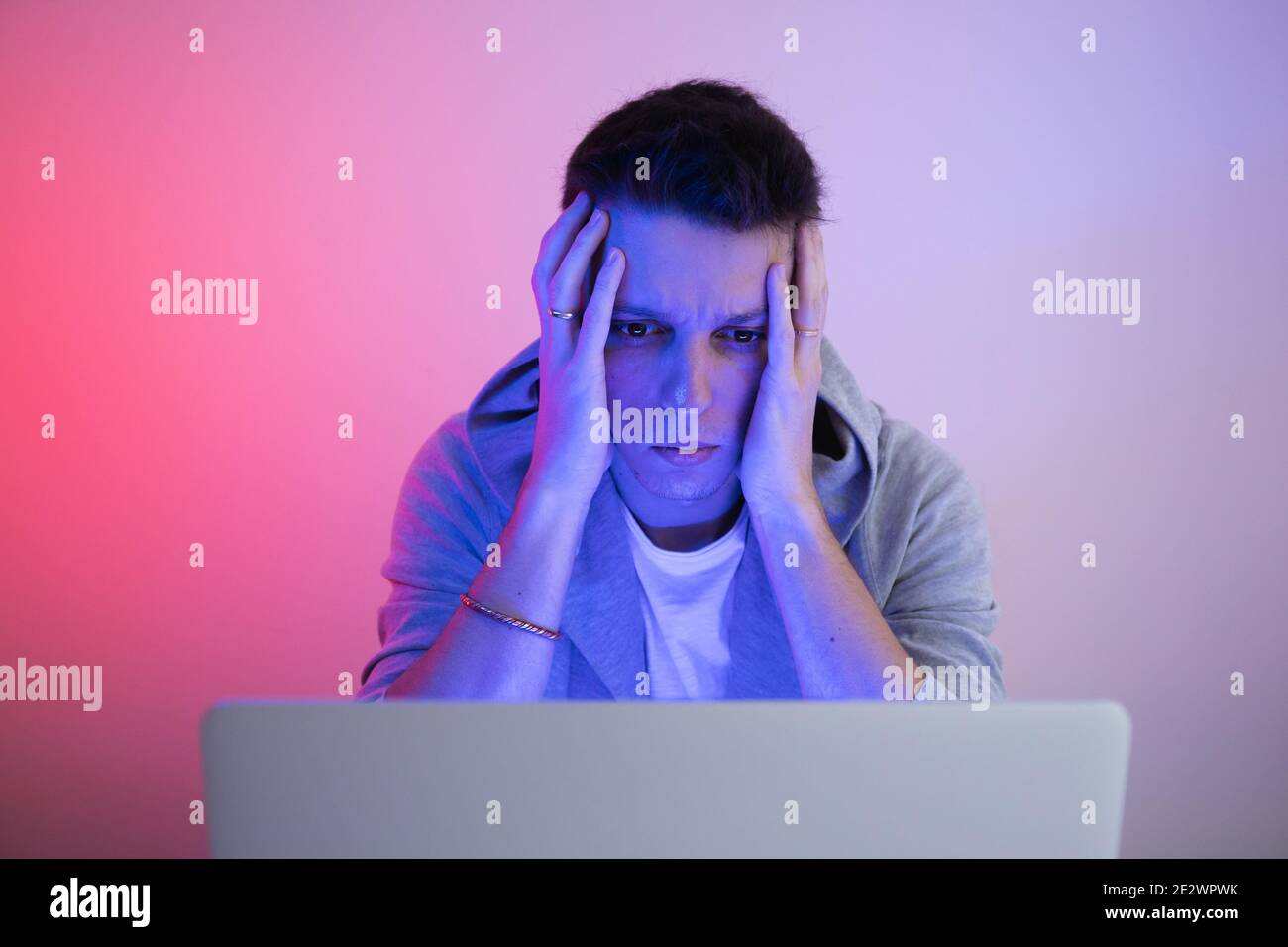 Gamer plays on a laptop. The programmer writes the code. Man on a colored background Stock Photo