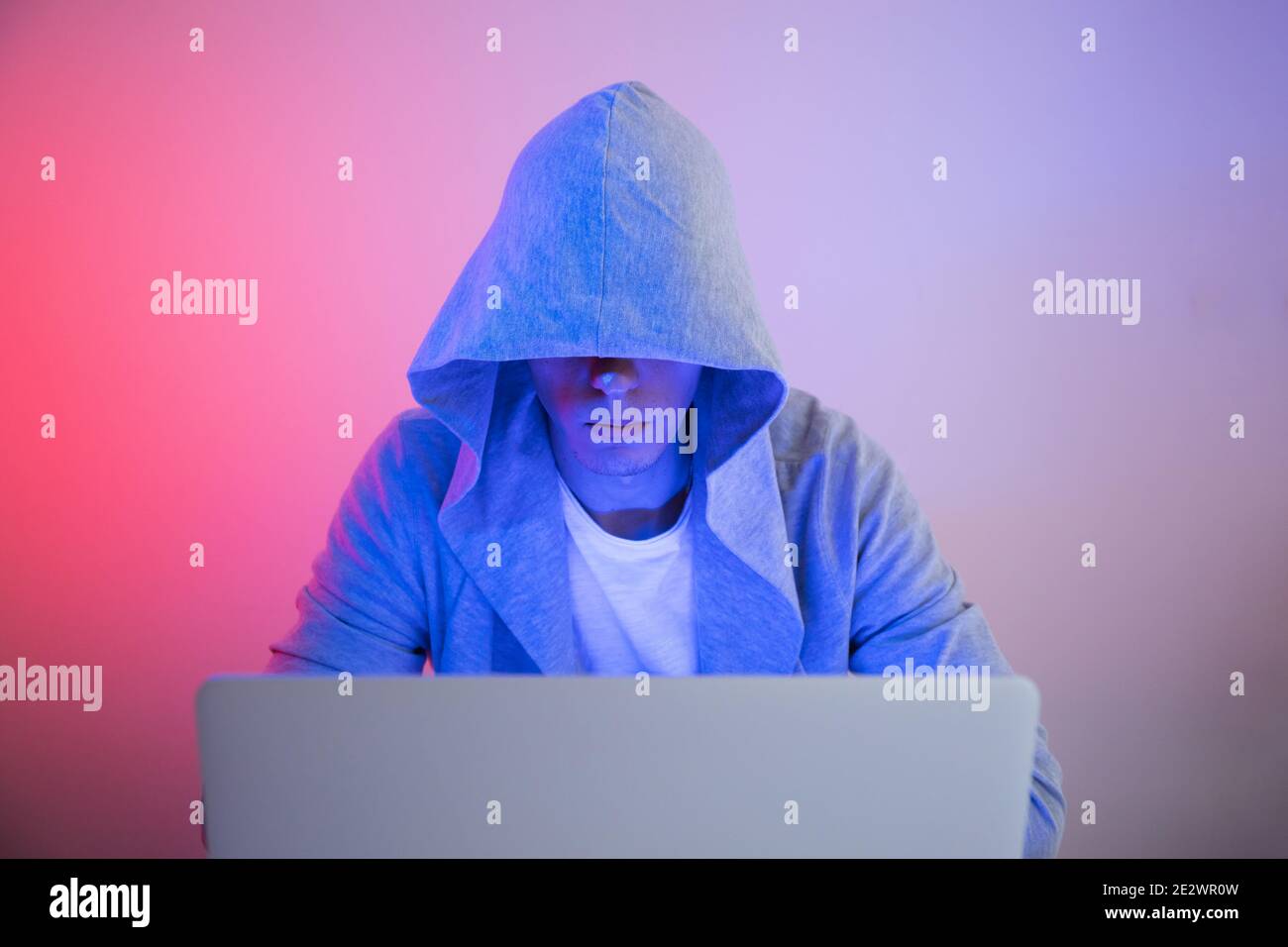 Gamer plays on a laptop. The programmer writes the code. Man on a colored background Stock Photo