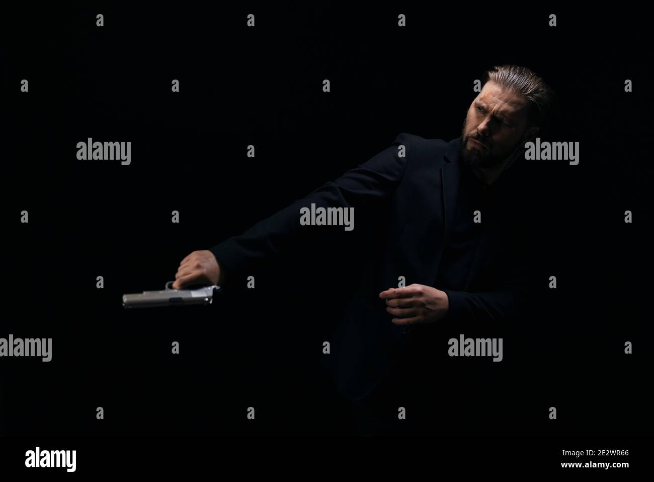 Brutal killer posing in studio with gun in hands Stock Photo