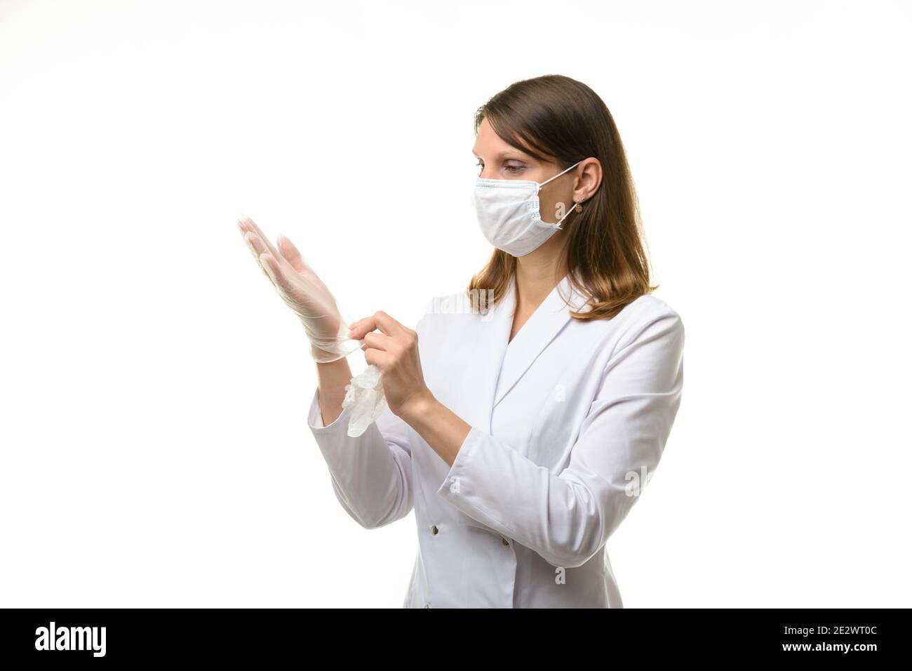 Girl doctor puts on transparent medical gloves on her hands Stock Photo