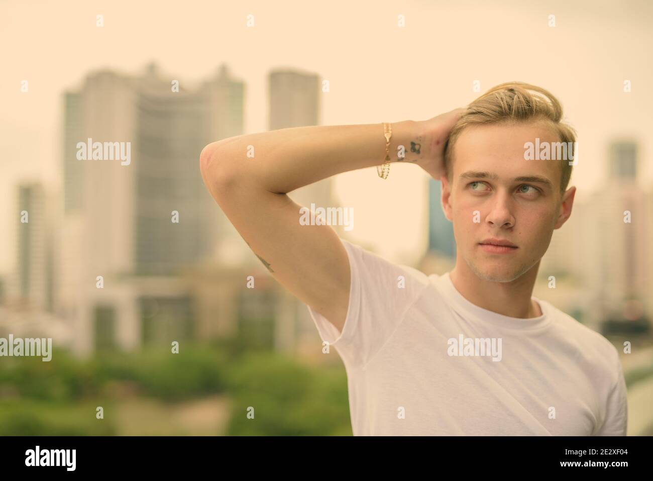 Young handsome man with blond hair against view of the city Stock Photo ...