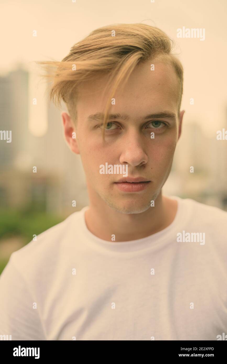 Young handsome man with blond hair against view of the city Stock Photo ...