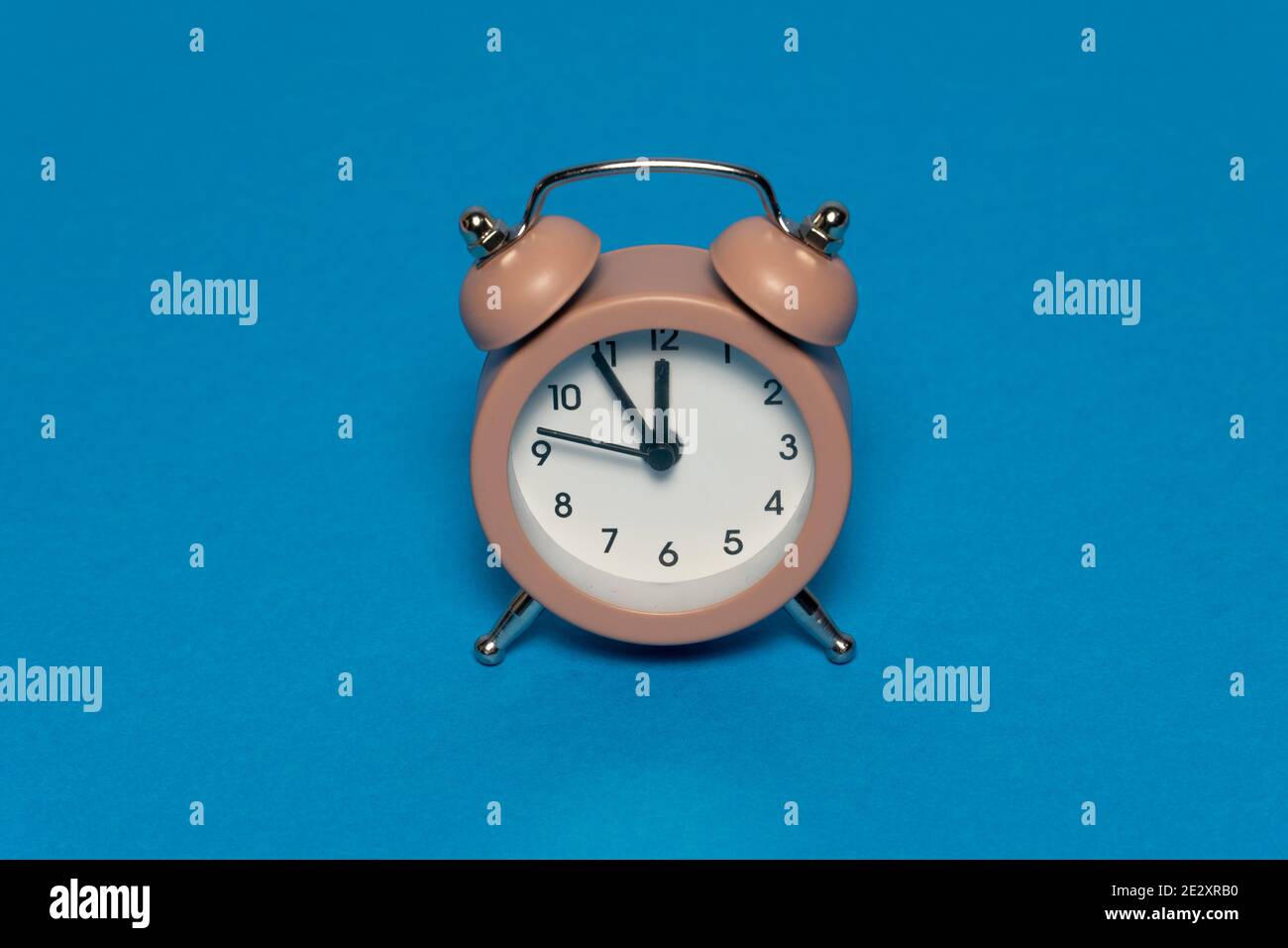 Brown alarm retro clock on blue background. Five minutes to twelve. Creative time concept Stock Photo