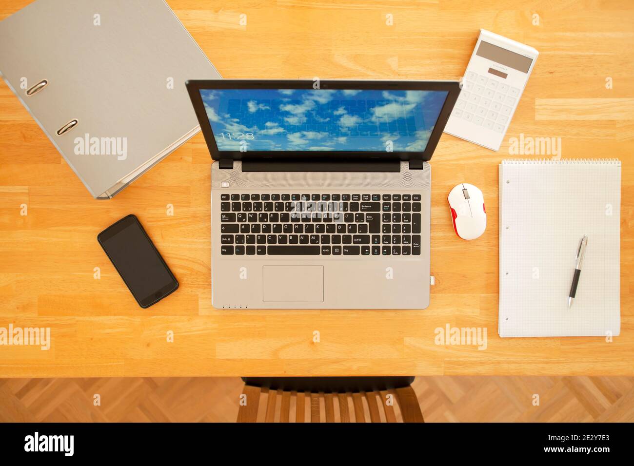 Overhead view of a workplace at home - wooden table with laptop, smart phone, calculator, file and mouse - overhead view - the photo an the sreen was Stock Photo