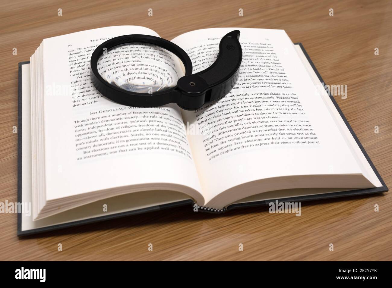 Open book with magnifying glass on the table Stock Photo - Alamy