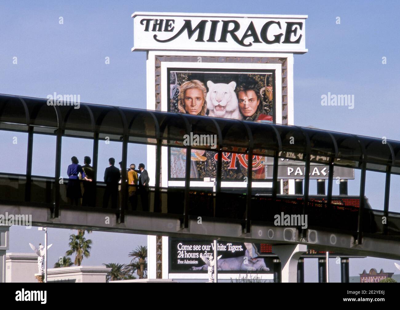 Visiitors on walkway to the Caesar's Palace Casino look out over a large marquee sign for the Mirage Hotel promoting a perofrmance by magicians Sigfri Stock Photo