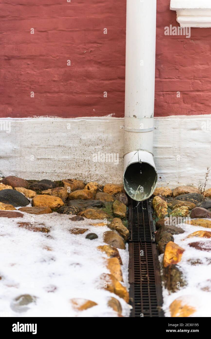 Storm water drain. Gutter from the roof. Water is poured out of the gutter into the grate. Stock Photo
