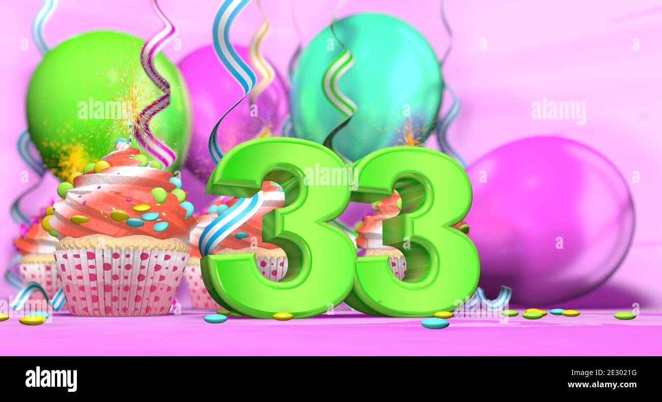Birthday cupcake with sparking candle with the number 33 large in green with cupcakes with red cream decorated with chocolate chips and balloons on th Stock Photo