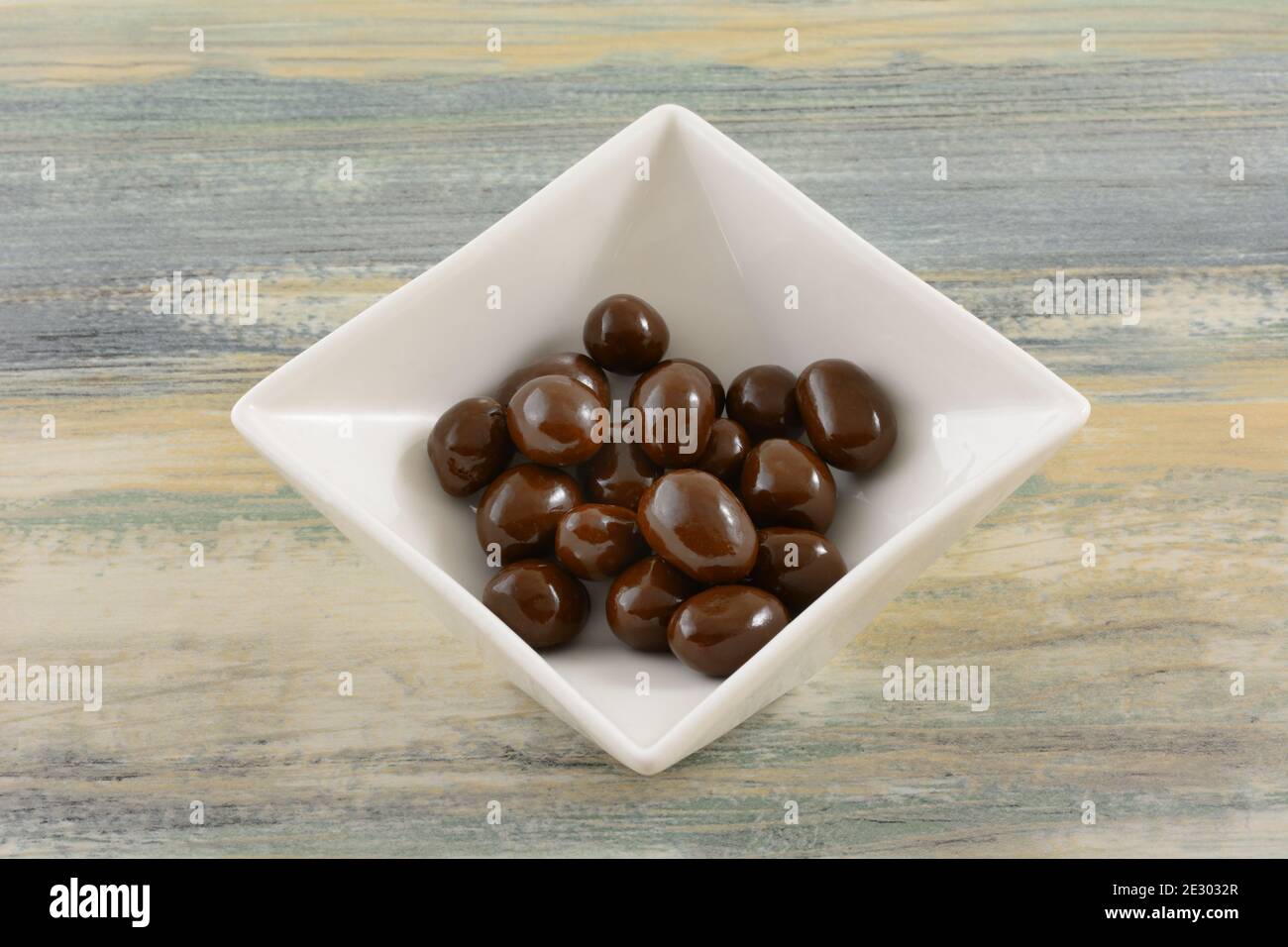 Chocolate covered peanuts candy in white candy dish on table Stock Photo