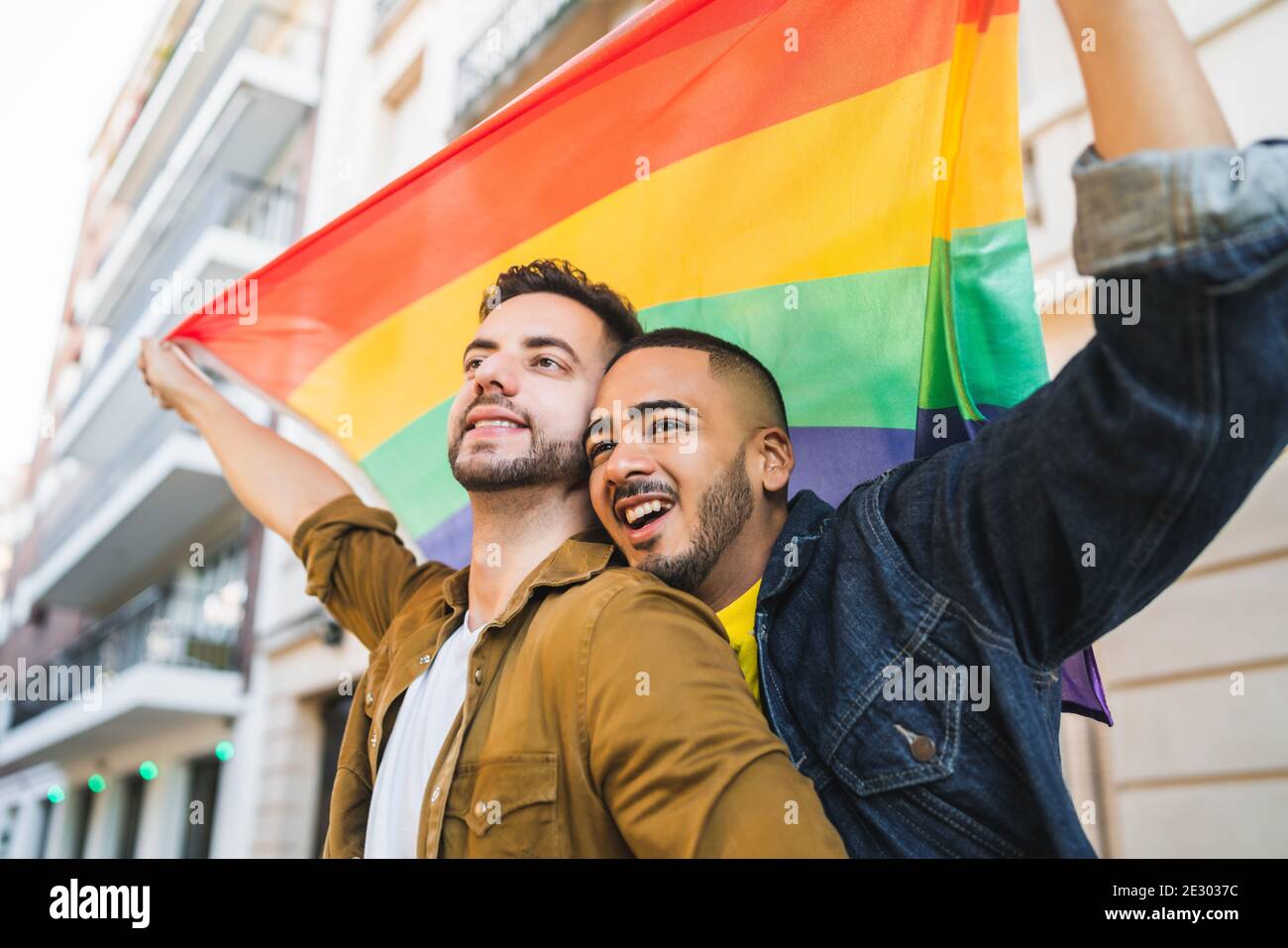 Gay couple embracing and showing their love with rainbow flag Stock ...