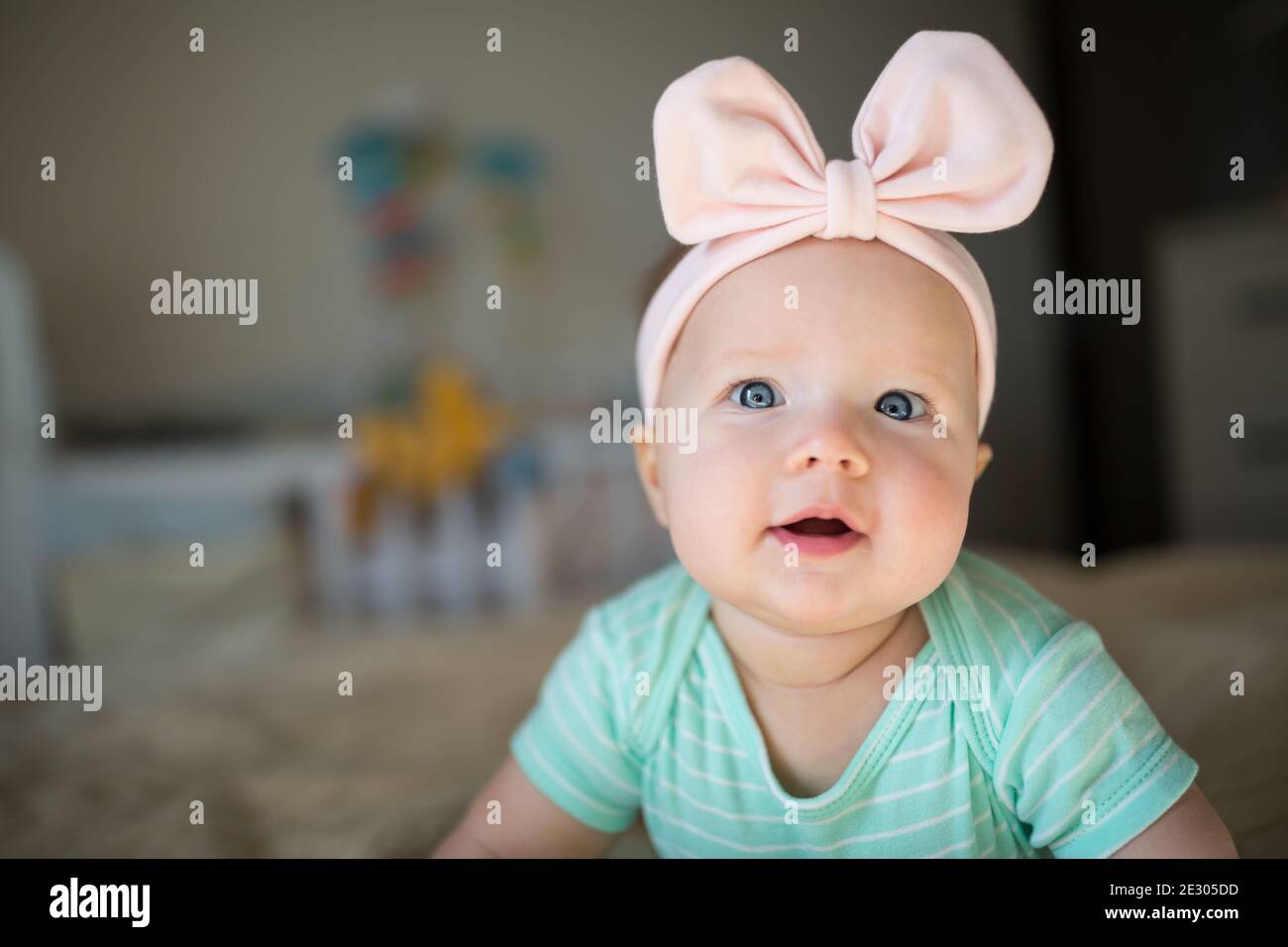 Caucasian blonde baby six months old lying on cozy knitted blanket at home. Kid wearing cute