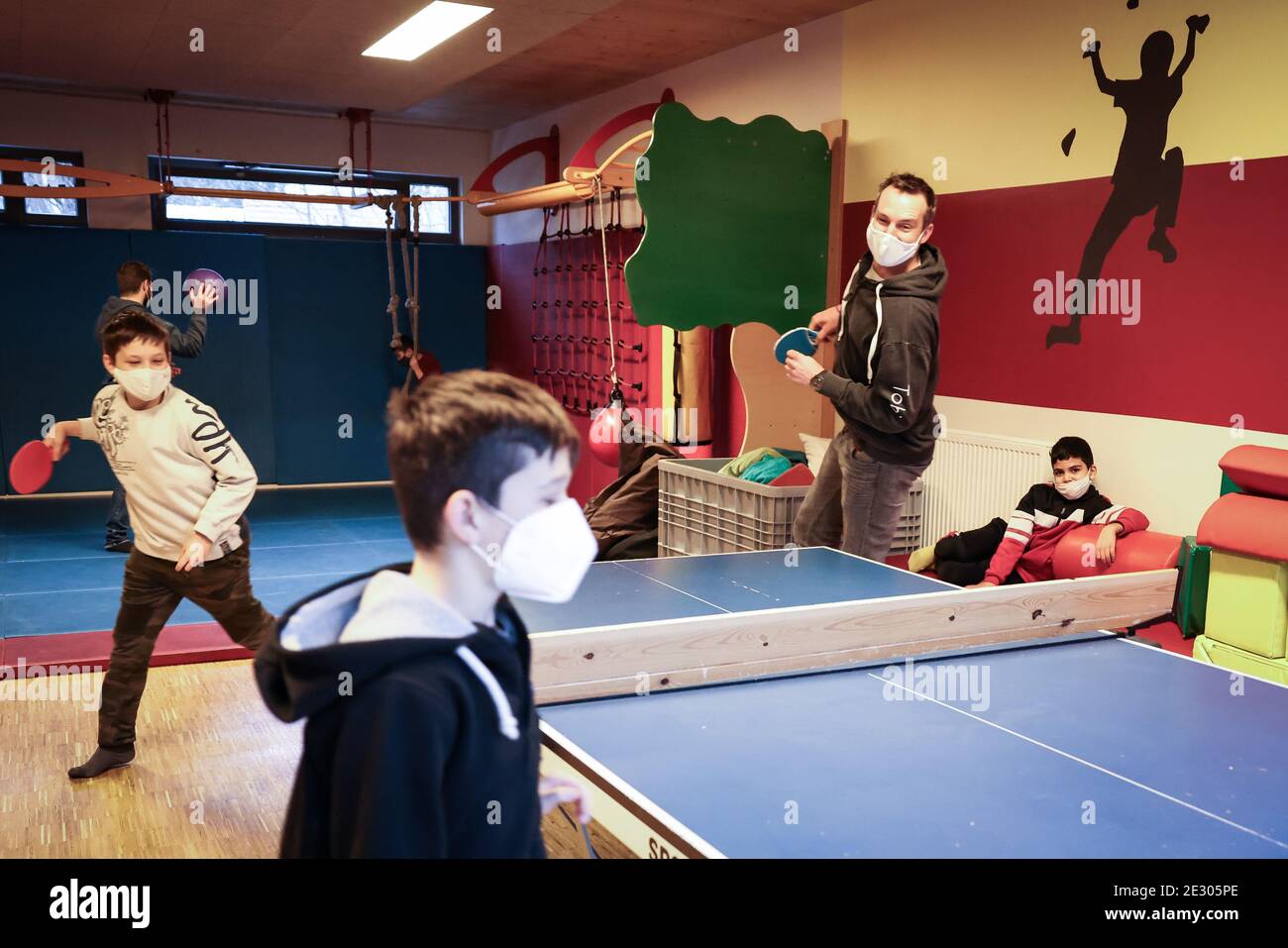 Hamburg, Germany. 15th Jan, 2021. Tobias Lucht, regional director of Arche  Hamburg, plays table tennis with three boys in the sports room of the Arche  children's project in Hamburg-Jenfeld. The lockdown due