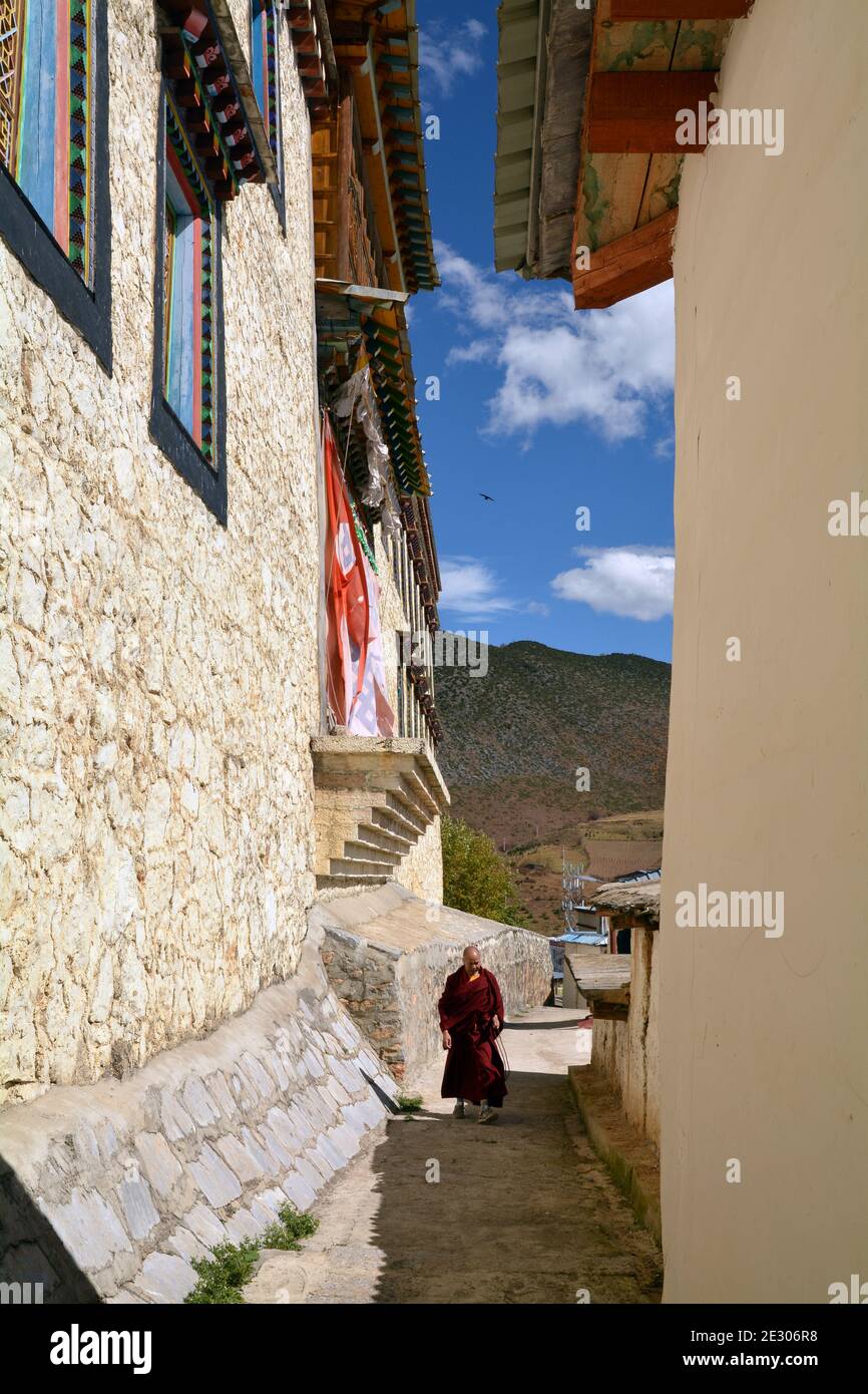 Sumtseling monastery high above the city of Shangri La, Yunnan. Tibetan style with gold topped buildings. A monk walks through the narrow lanes Stock Photo
