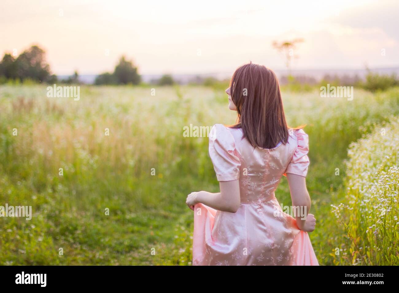 girl standing in the field in a pink dress Stock Photo - Alamy