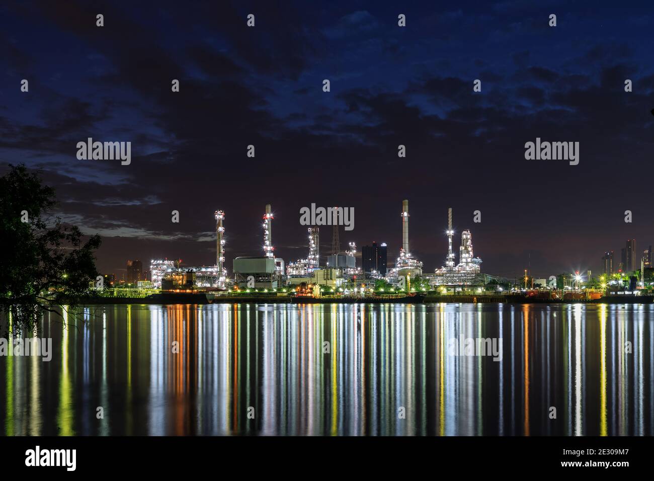 Oil and gas refinery plant factory with refection on river at night twilight. petrochemical and energy industry concept. Stock Photo