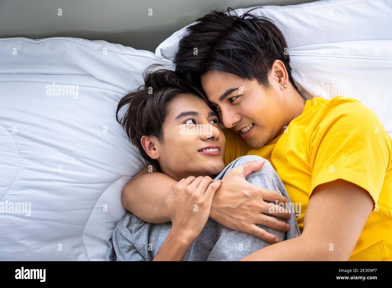 Happy Asian homosexual gay men male couple lying and embracing on bed. LGBT and sexual diversity concept. Stock Photo