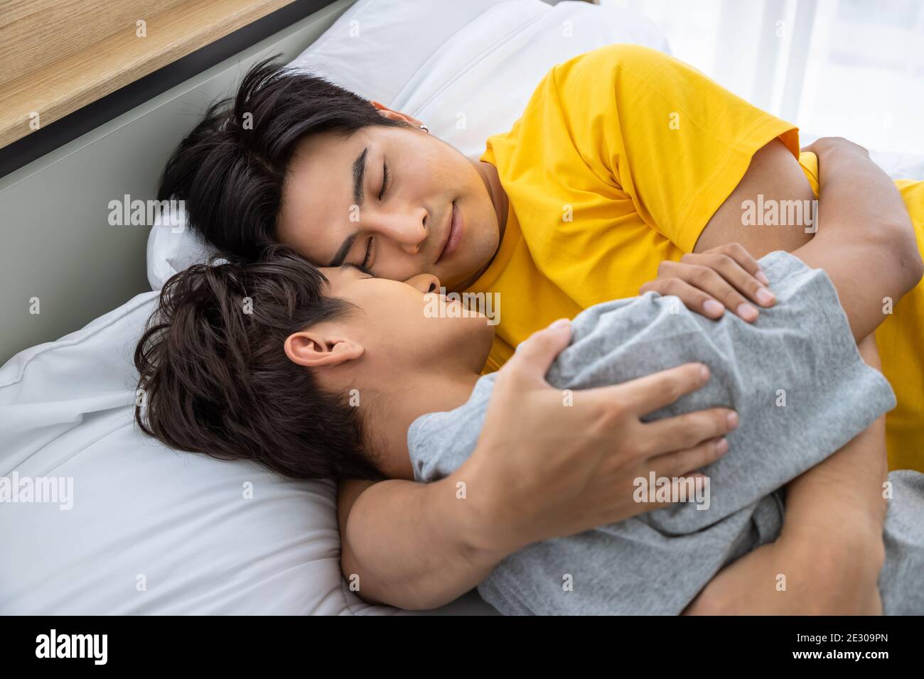 Happy Asian homosexual gay men male couple lying and embracing on bed, sleeping together. LGBT and sexual diversity concept. Stock Photo