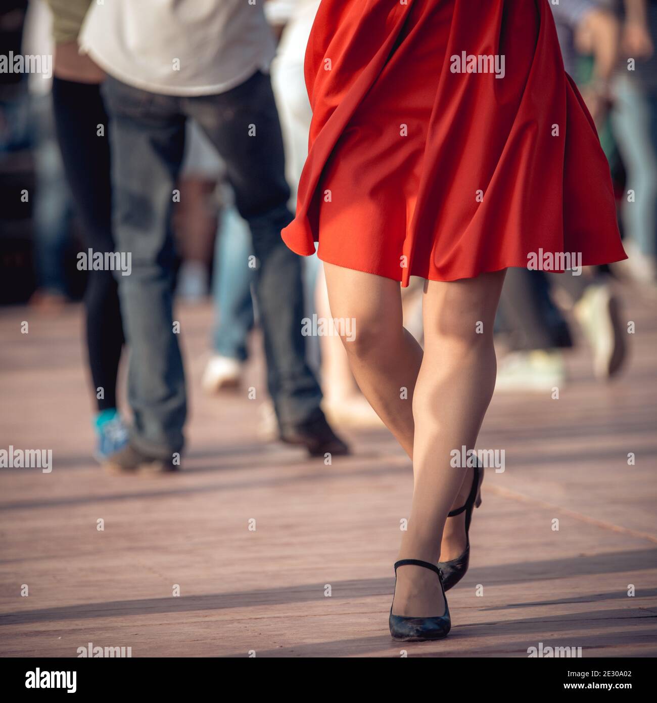 people are dancing outdoors in the park at sunny day. beautiful female feet in dancing shoes in the foreground and red skirt Stock Photo