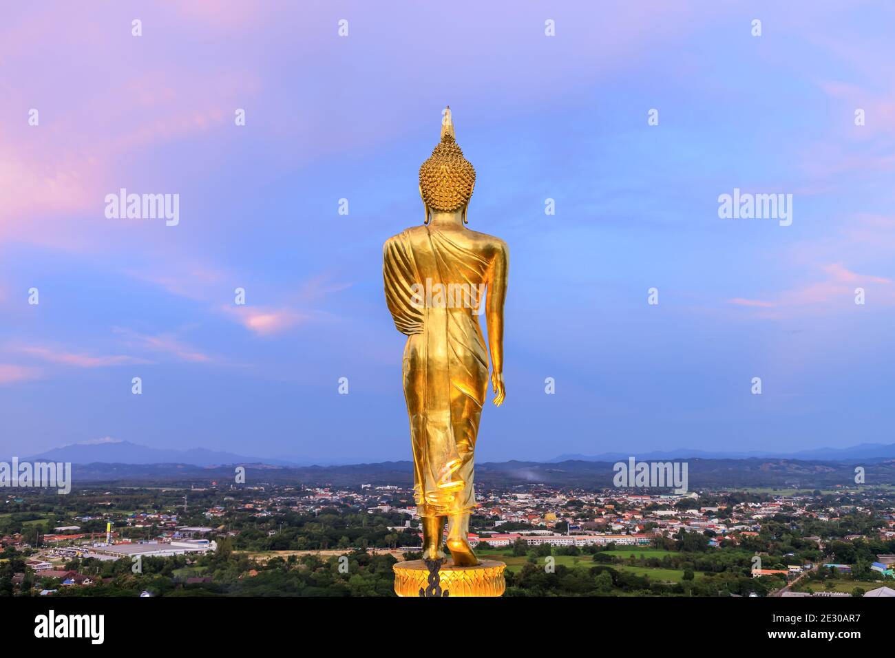 Golden walking Buddha statue on hill or mountain to at Wat Phrathat Khao Noi temple during twilight, Nan province, Thailand Stock Photo