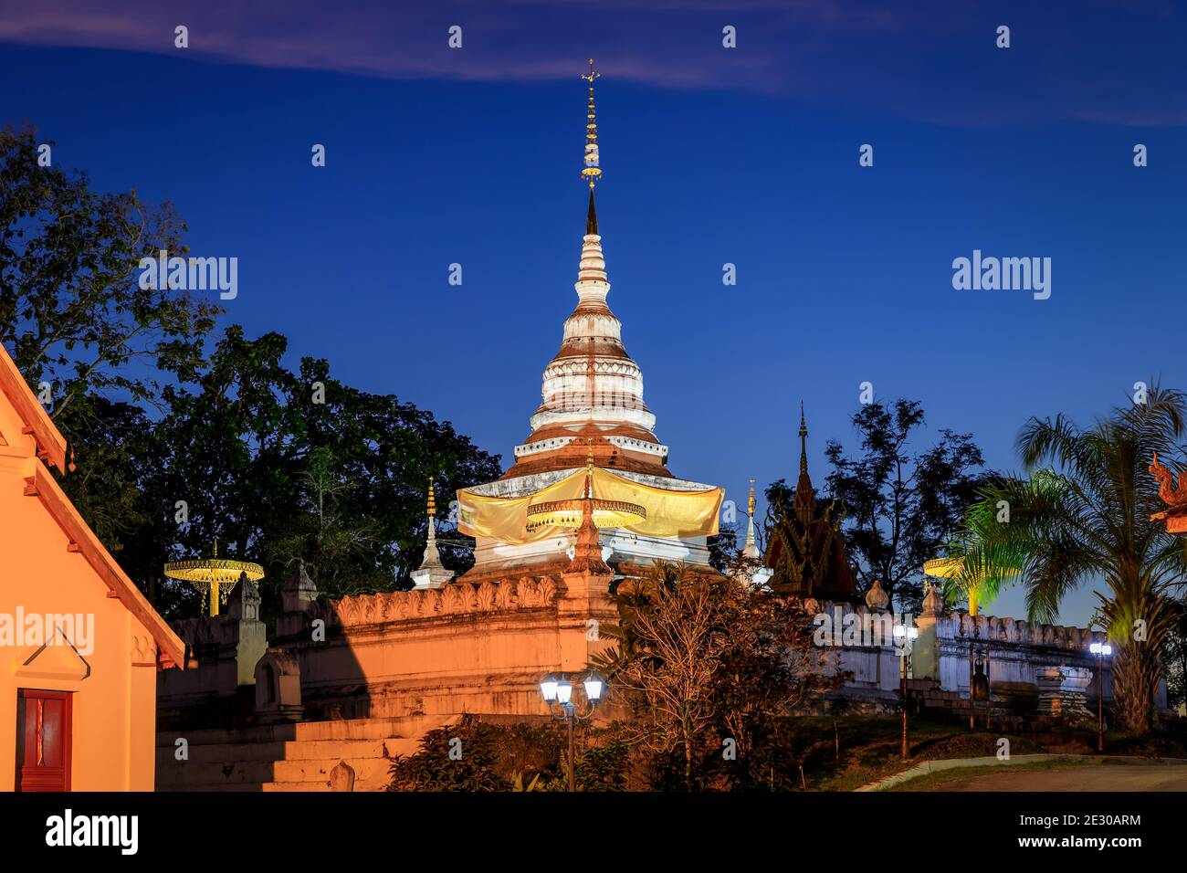 Golden pagoda and chapel on hill or mountain to at Wat Phrathat Khao Noi temple during twilight, Nan province, Thailand Stock Photo