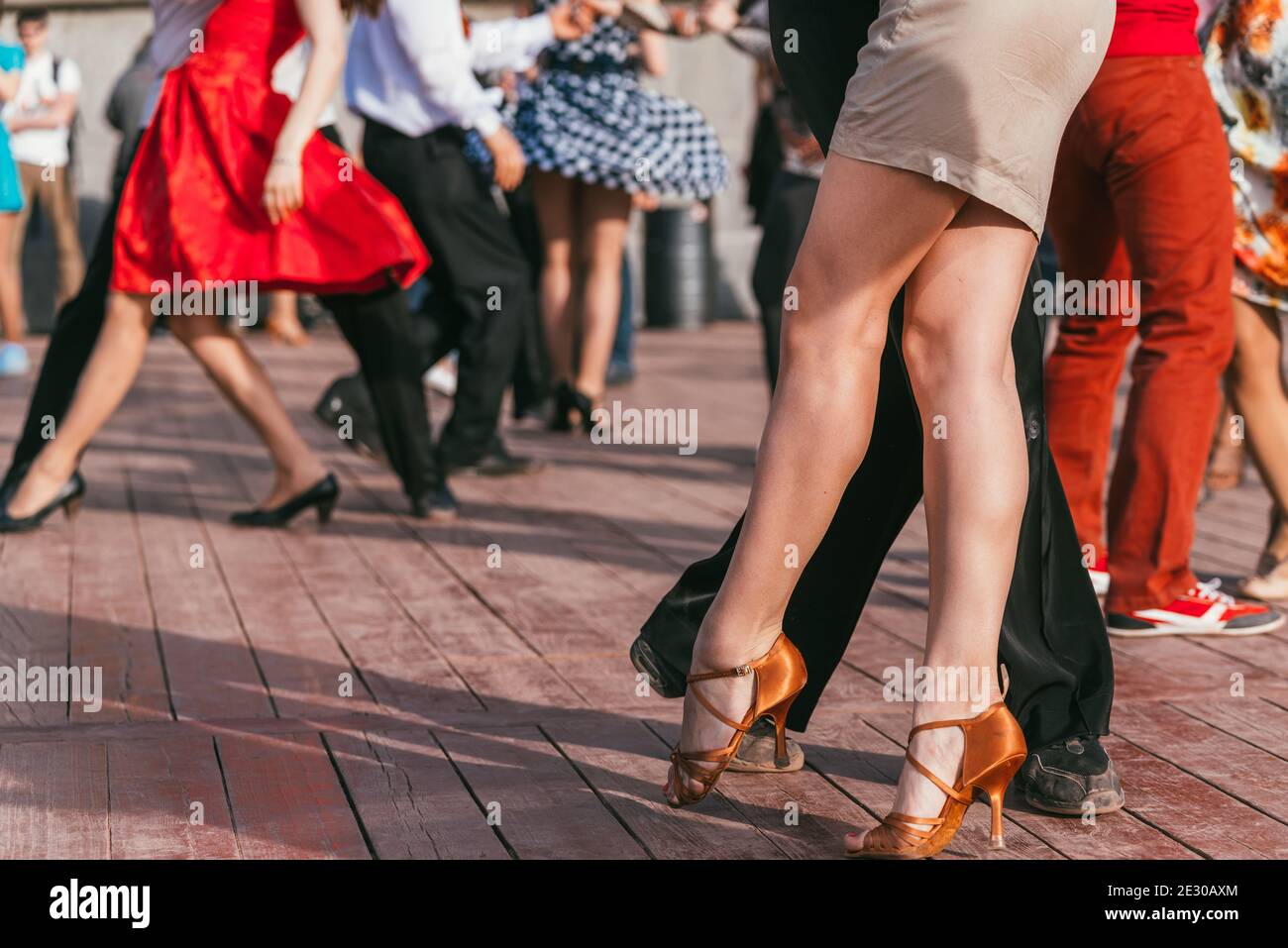 people are dancing outdoors in the park at sunny day. beautiful female feet in dancing shoes in the foreground and background and red skirt Stock Photo