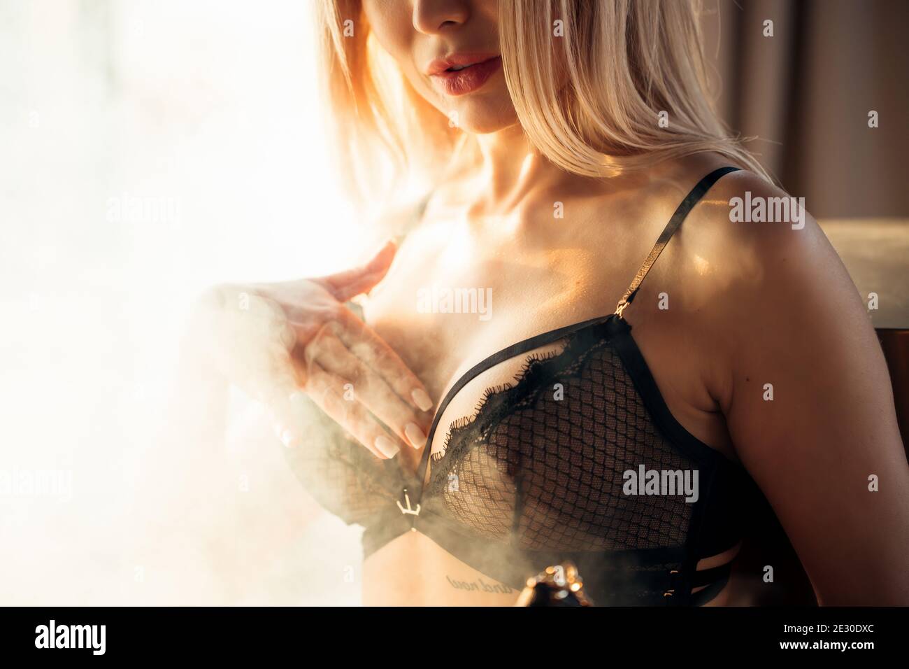Woman in black lingerie, big silicone breasts, closeup. Beautiful manicure, white haze Stock Photo