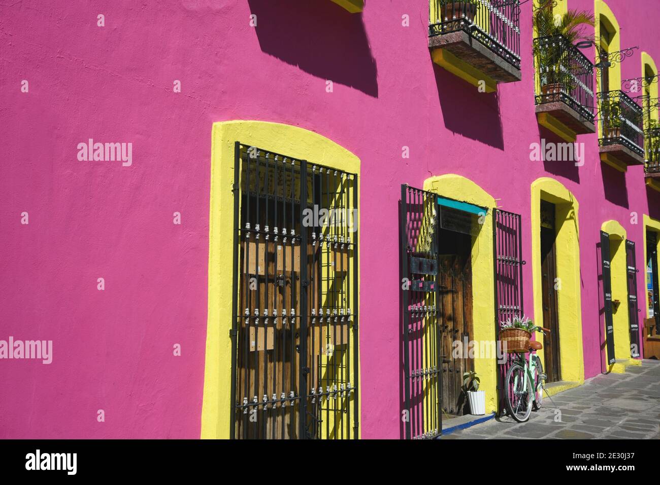 Colonial style local souvenir shop facade with a pink stucco wall, yellow trimmed windows and