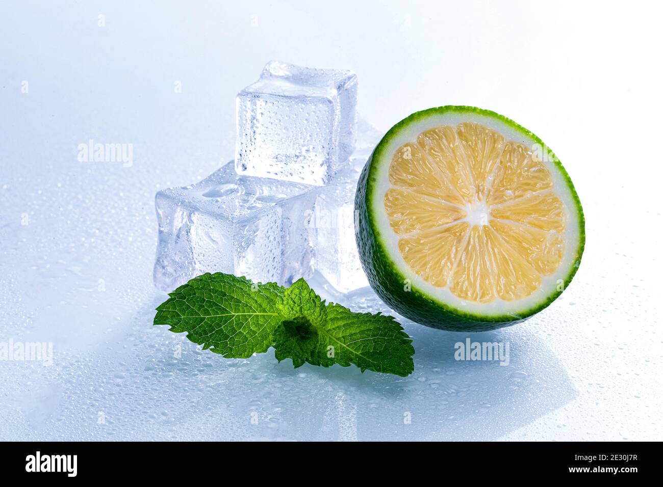Selective focus shot of melting ice cubes and a half of lime with mint ...