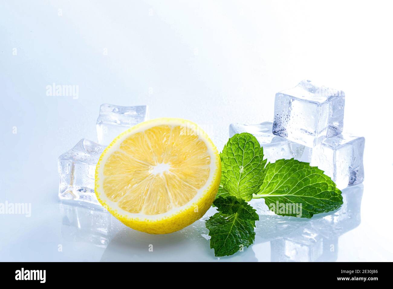 Selective focus shot of melting ice cubes and a half of lemon with mint ...