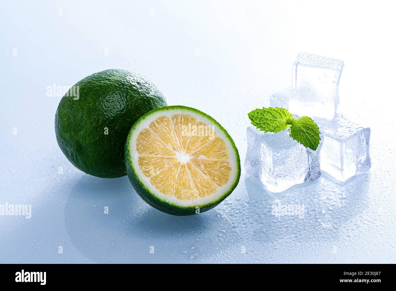 Selective focus shot of melting ice cubes and a half of lime with mint ...