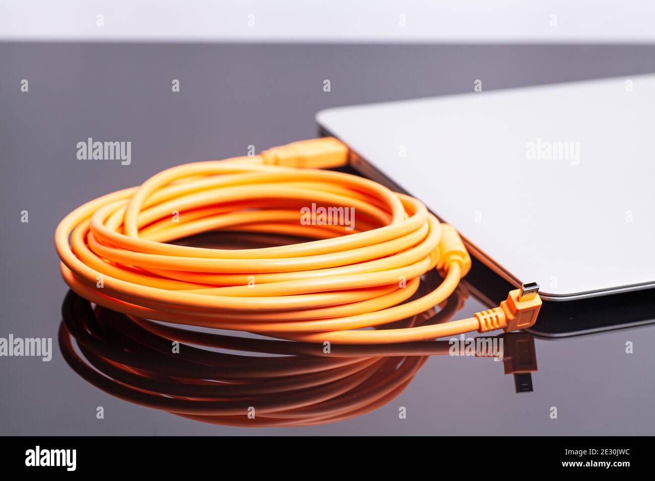 laptop with orange rolled cable. Stock Photo