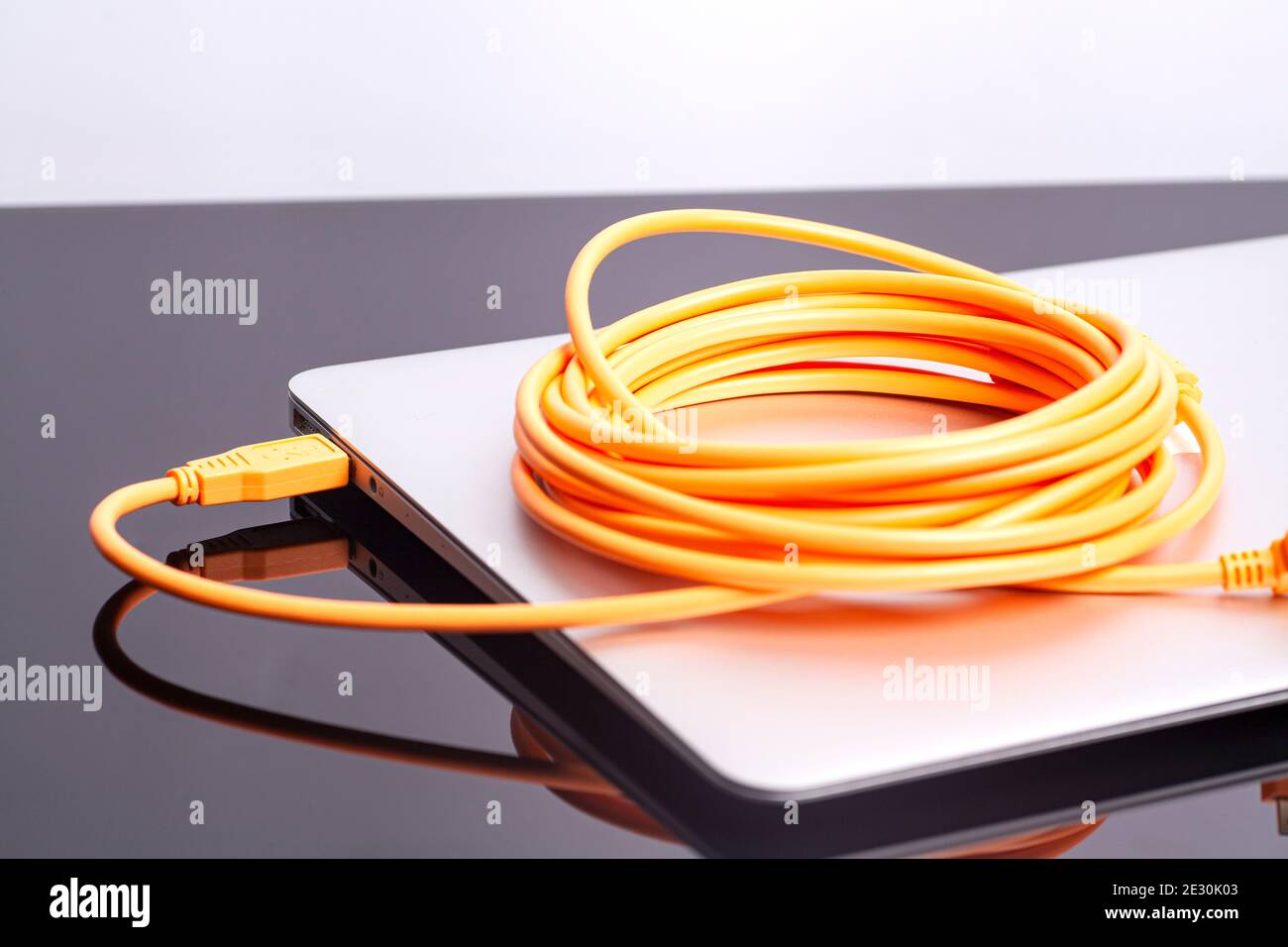 laptop with orange rolled cable. Stock Photo