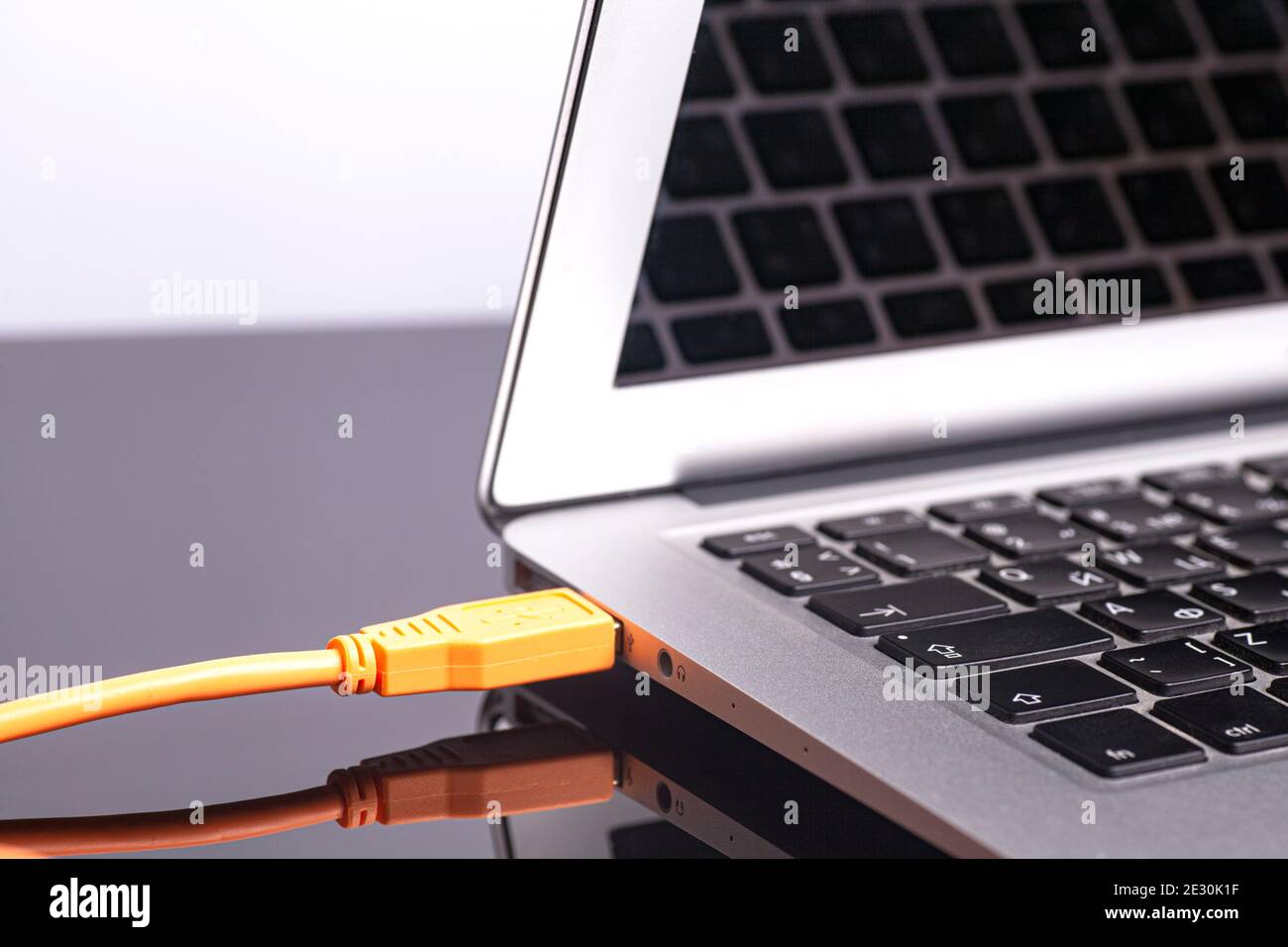 laptop with orange rolled cable. Stock Photo