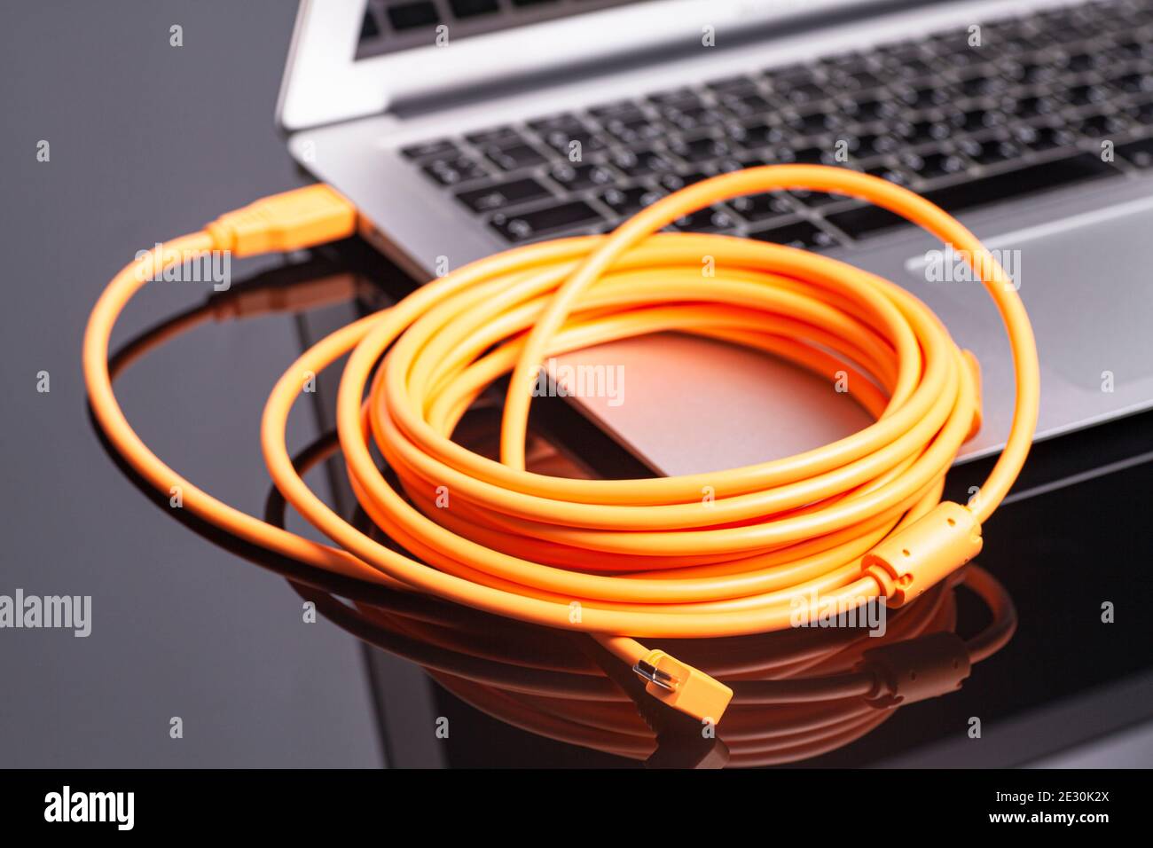 laptop with orange rolled cable. Stock Photo
